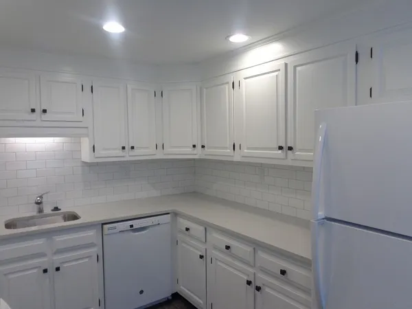 a kitchen with white cabinets and white appliances