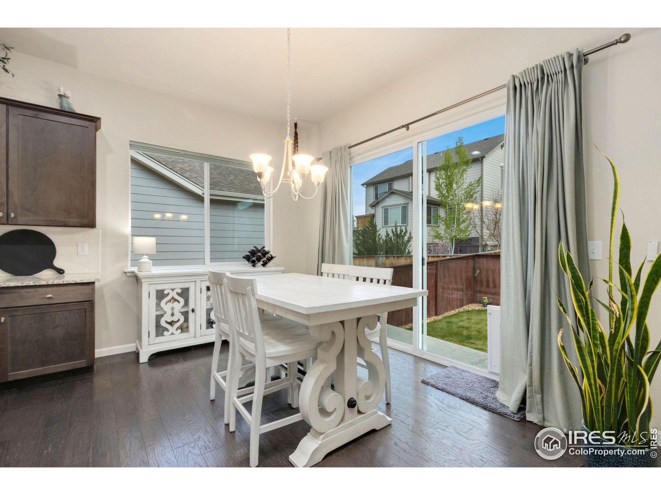 719 Wagon Bend Road Berthoud, CO 80513 - Photo 14 of 40 a open kitchen with stainless steel appliances kitchen island granite countertop a refrigerator a stove a dining table and chairs with wooden floor