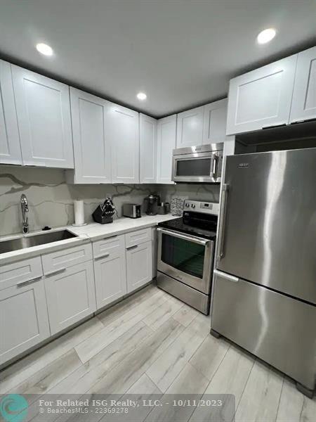 2301 Collins Avenue, Unit 327 Miami Beach, FL 33139 - Photo 6 of 11 a kitchen with stainless steel appliances granite countertop a refrigerator sink and cabinets