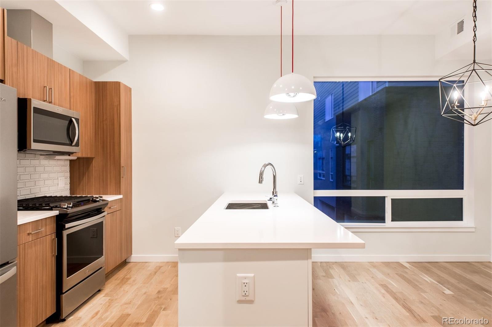 910 West 40th Avenue Denver, CO 80211 - Photo 27 of 33 a kitchen with stainless steel appliances kitchen island granite countertop a stove and a sink
