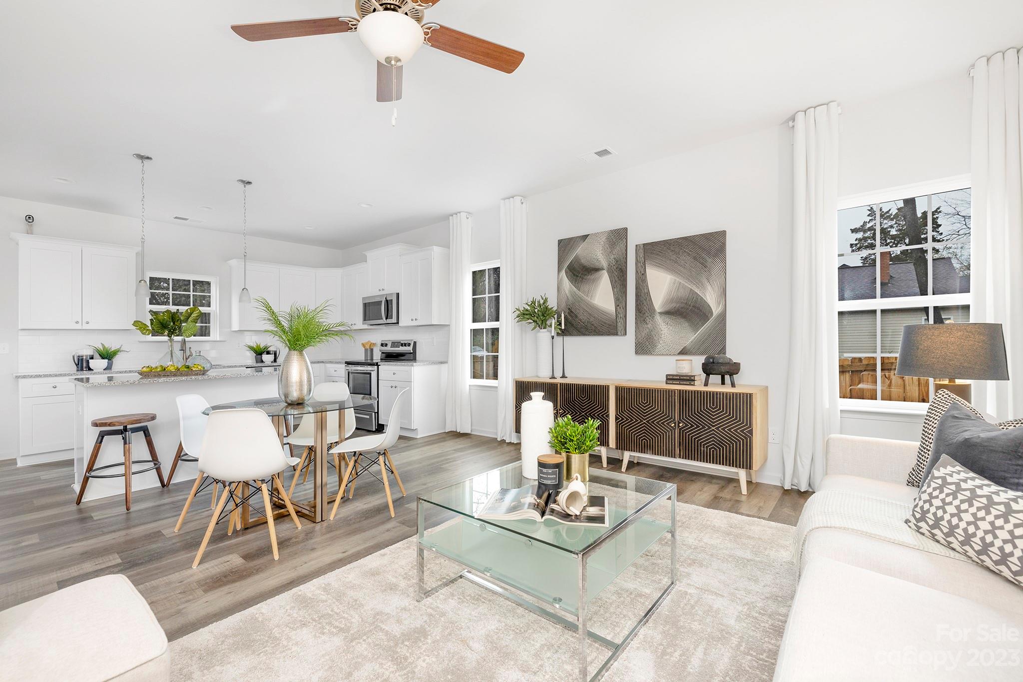 a living room with furniture kitchen view and a large window