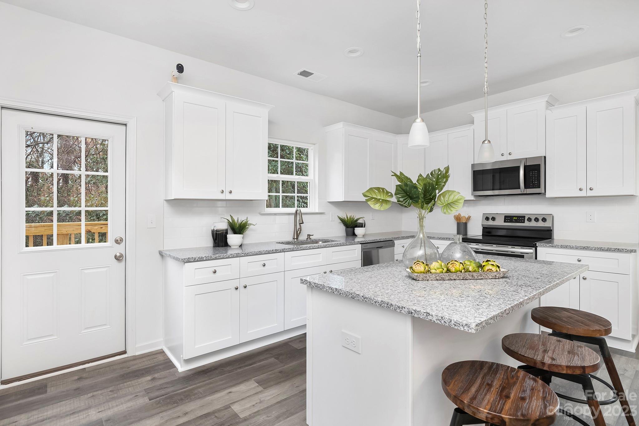 8725 Mt Holly Road Charlotte, NC 28214 - Photo 8 of 19 a kitchen with a sink dishwasher stove and white cabinets with wooden floor
