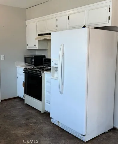 a utility room with stainless steel appliances white cabinets and a refrigerator