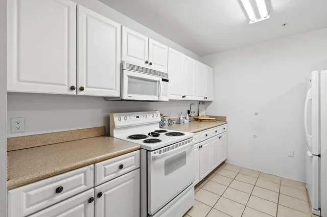 a kitchen with granite countertop white cabinets and white appliances