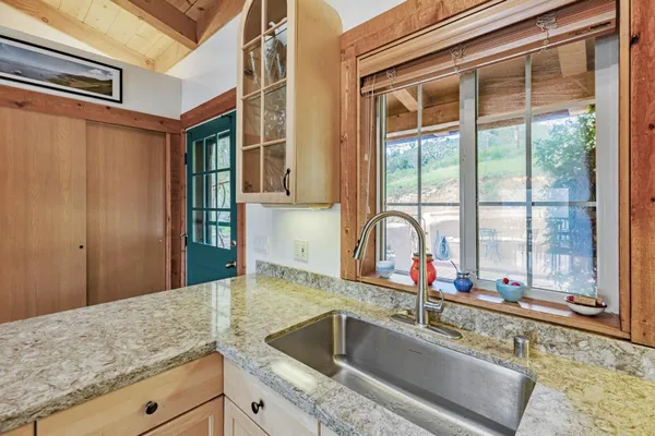 a kitchen with a granite countertop sink and natural light