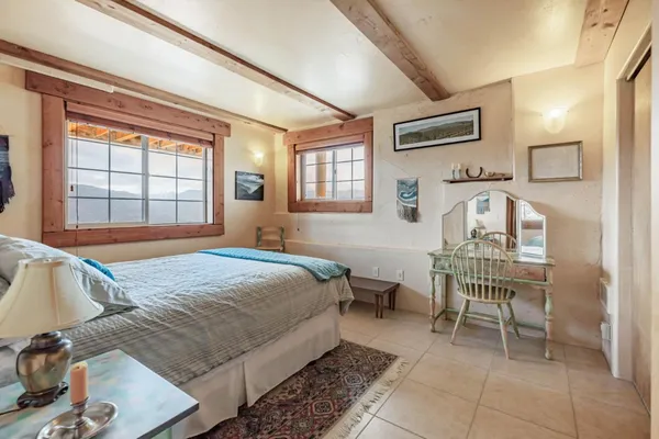a bedroom with a bed a chair and next to a window