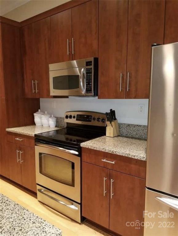 230 South Tryon Street, Unit 508 Charlotte, NC 28202 - Photo 4 of 24 a kitchen with stainless steel appliances granite countertop a stove microwave and refrigerator