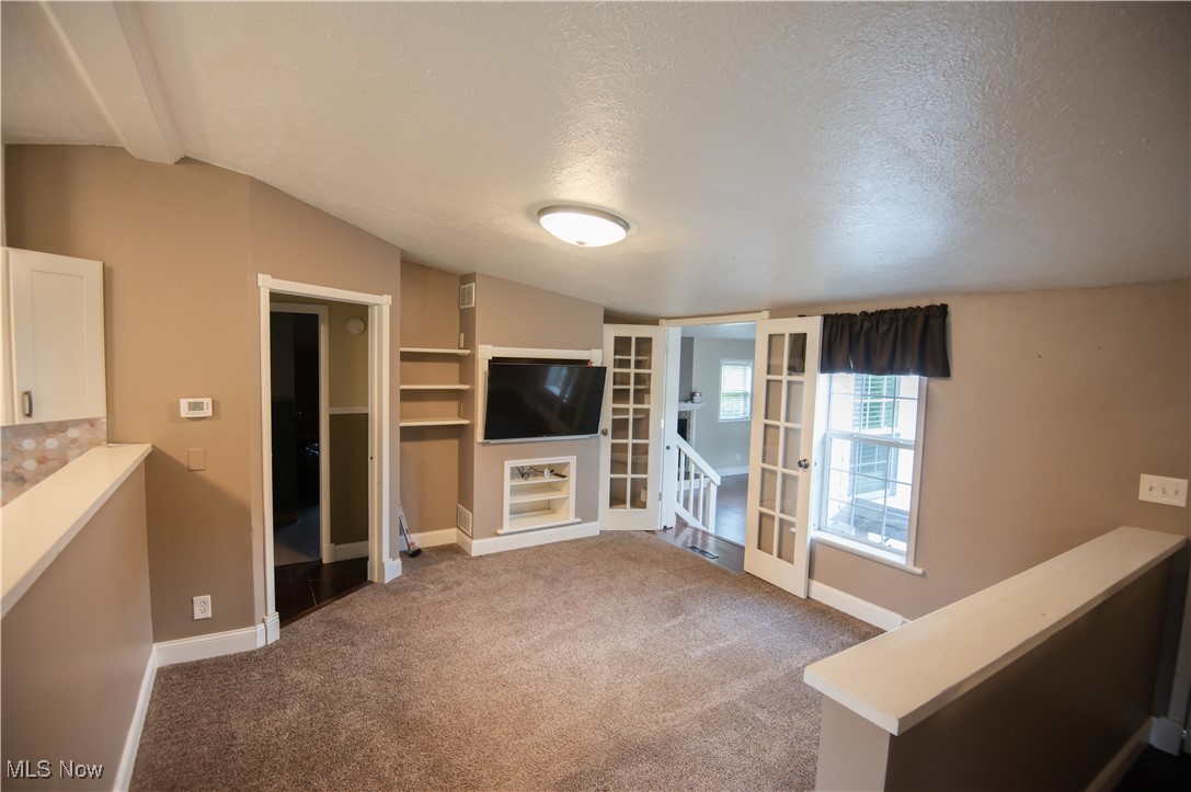 4594 Center Road Andover, OH 44003 - Photo 9 of 39 Unfurnished living room with lofted ceiling, dark colored carpet, and a textured ceiling