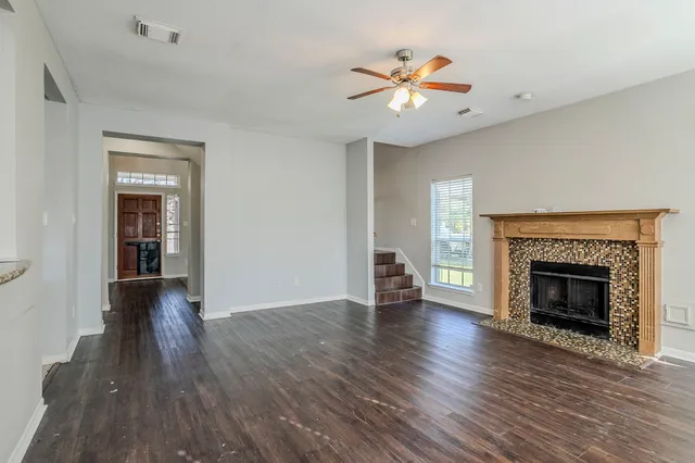 a view of an empty room with wooden floor fireplace and a window