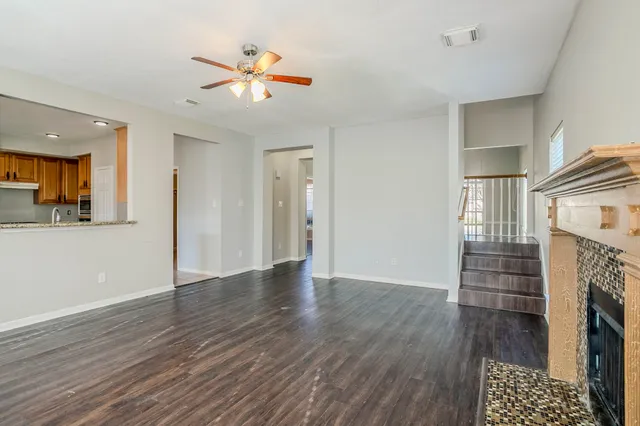 an empty room with wooden floor a ceiling fan and a window