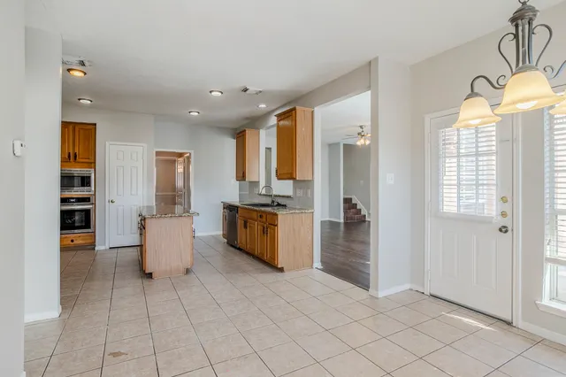 a large white kitchen with stainless steel appliances granite countertop a refrigerator and a sink
