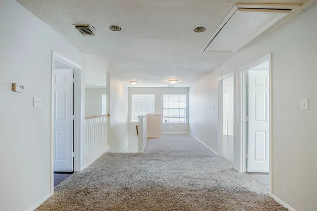 a view of a hallway with wooden cabinet and door