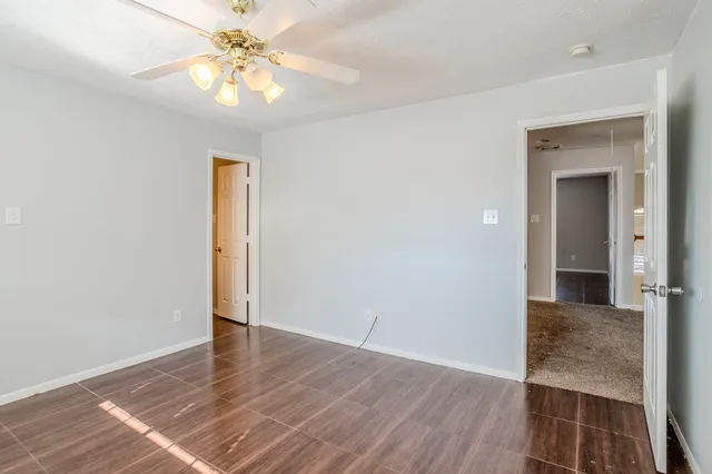 an empty room with wooden floor and a ceiling fan
