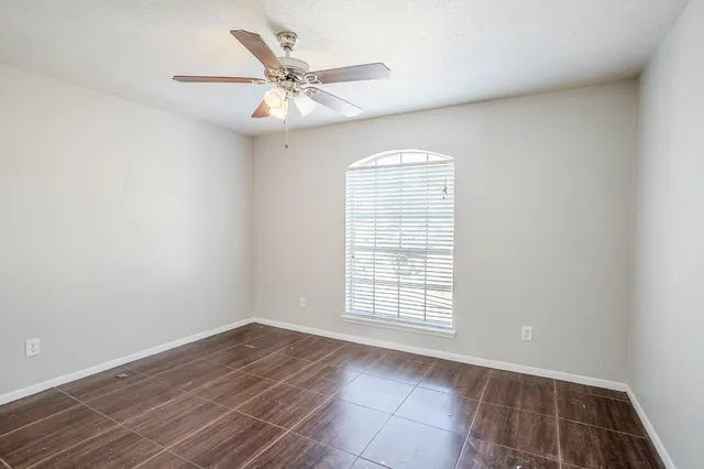 an empty room with wooden floor fan and windows