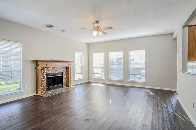 a view of an empty room with wooden floor fireplace and a window
