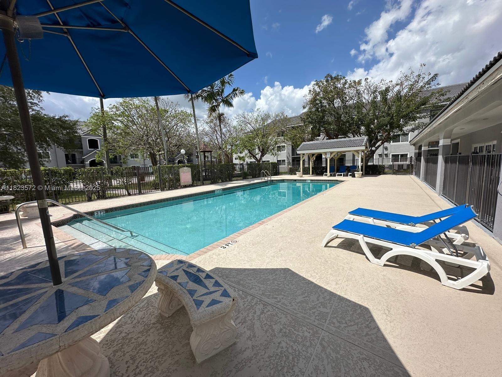 15422 Southwest 284th Street, Unit 7207 Homestead, FL 33033 - Photo 32 of 36 a view of pool with lawn chairs under an umbrella