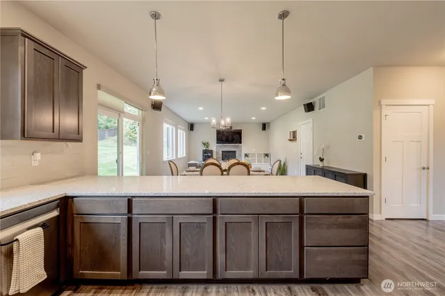 a room with kitchen island granite countertop a sink cabinets and wooden floor