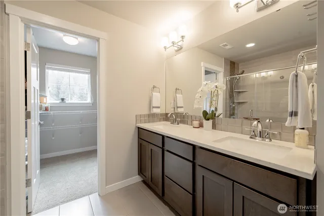 a bathroom with a double vanity sink mirror and shower