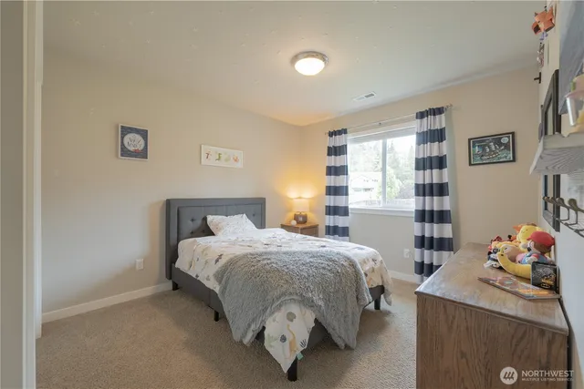 a bed sitting in a bedroom next to a window and dresser