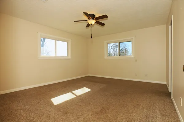 an empty room with a ceiling fan and window