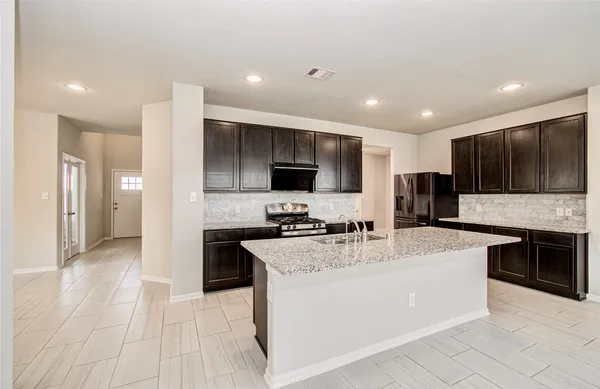 a large kitchen with stainless steel appliances kitchen island granite countertop a stove a sink a refrigerator and a microwave