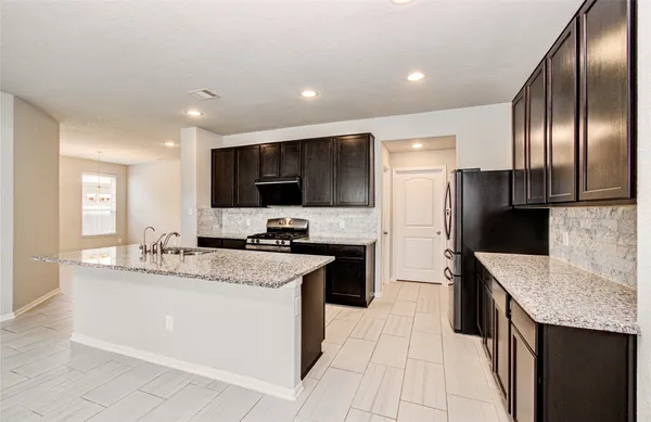 a kitchen with stainless steel appliances granite countertop a sink a stove a refrigerator a washer dryer and a refrigerator