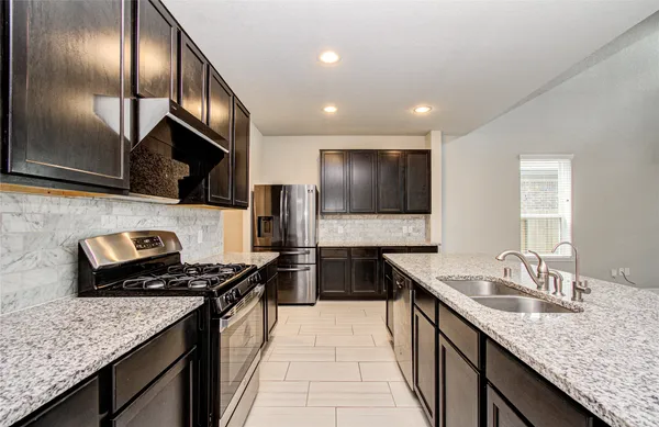 a kitchen with granite countertop stainless steel appliances a sink stove top oven and cabinets