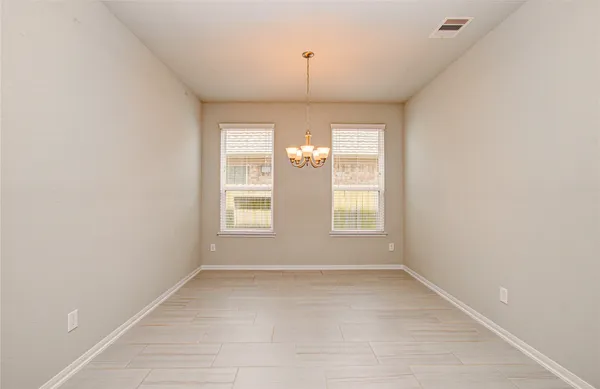 an empty room with chandelier fan and windows