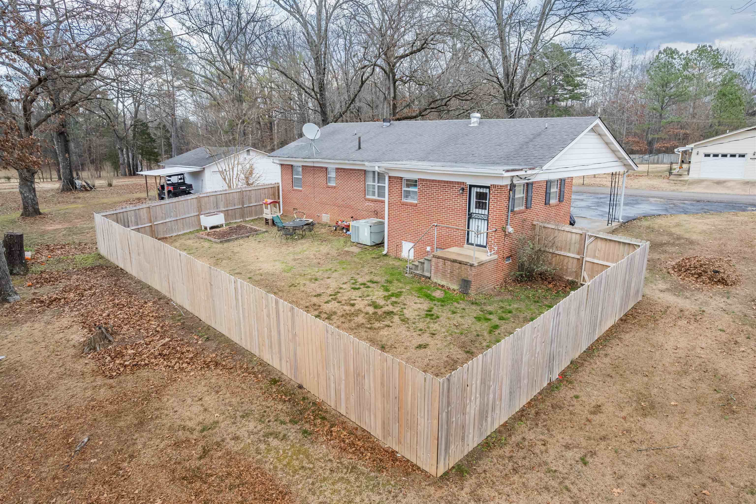 715 Burns Road Ramer, TN 38367 - Photo 8 of 20 View of home's exterior with brick siding, view of wooded area, a shingled roof, and a fenced backyard