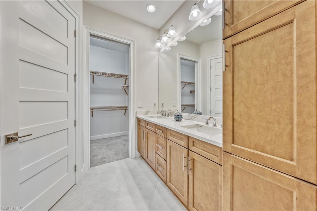 6421 Carnival Road Naples, FL 34113 - Photo 18 of 28 a bathroom with a double vanity sink a mirror and a shower