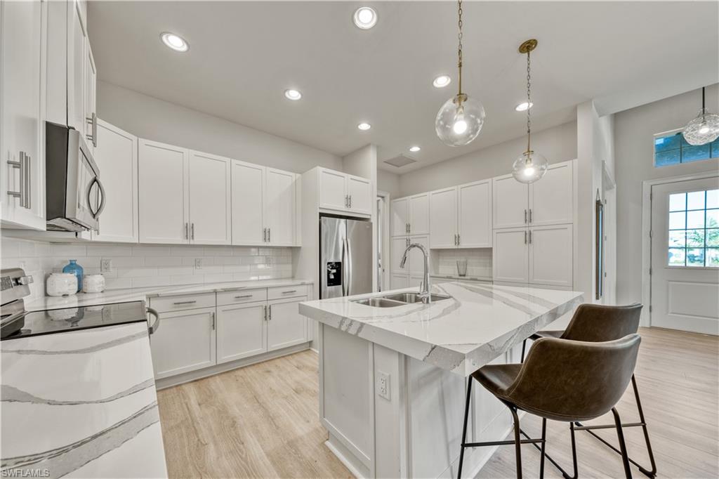 6421 Carnival Road Naples, FL 34113 - Photo 9 of 28 a kitchen with a dining table cabinets appliances and a counter top space