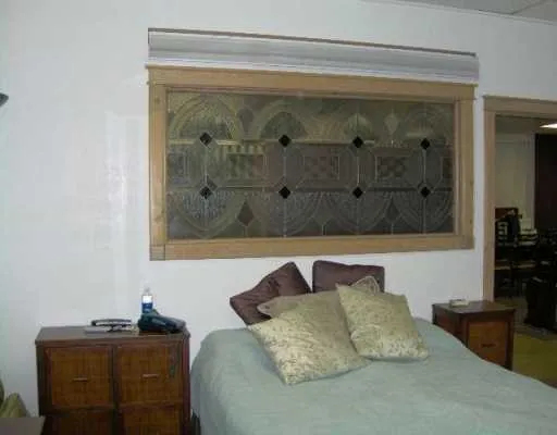 a bedroom with a bed and a potted plant on the dresser