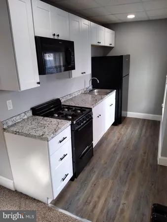 a kitchen with stainless steel appliances a white stove top oven a refrigerator a sink and dishwasher with wooden floor