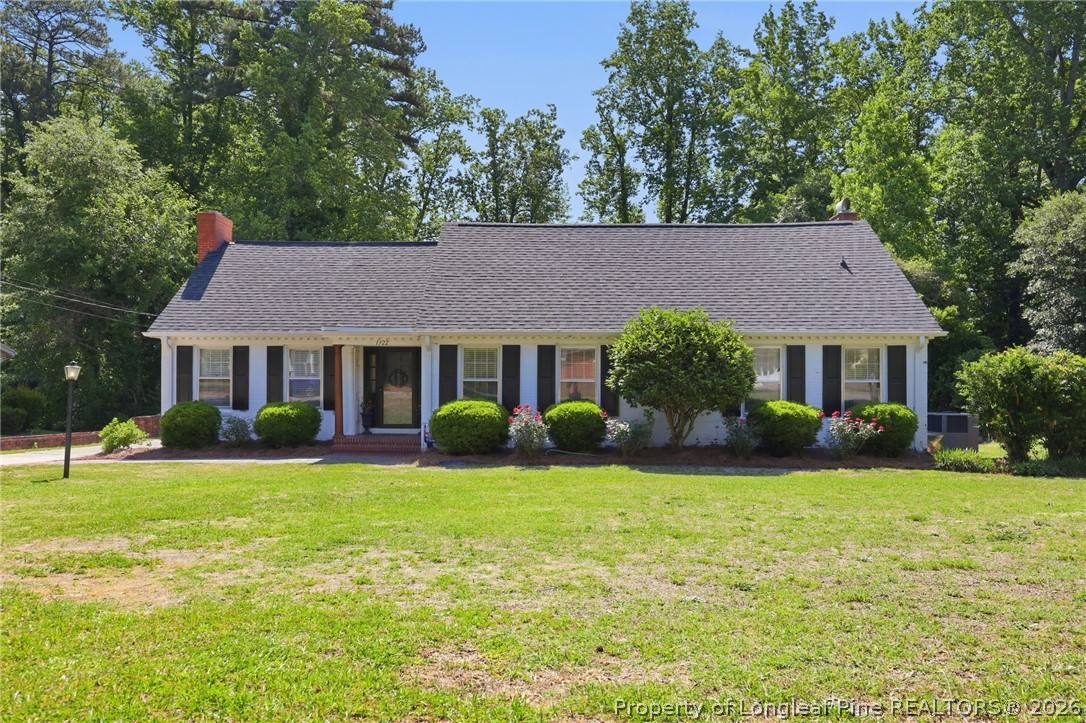 a front view of a house with garden and trees