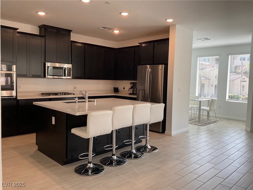 2555 Hampton Road, Unit 4209 Henderson, NV 89052 - Photo 11 of 67 Kitchen featuring dark cabinets, a breakfast bar area, stainless steel appliances, an island with sink, and recessed lighting