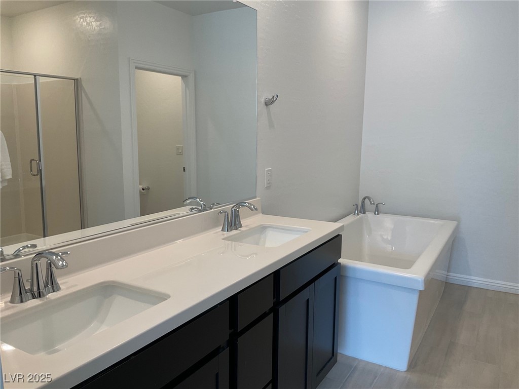 2555 Hampton Road, Unit 4209 Henderson, NV 89052 - Photo 43 of 67 Bathroom with double vanity, a freestanding tub, a shower stall, and light wood-style floors