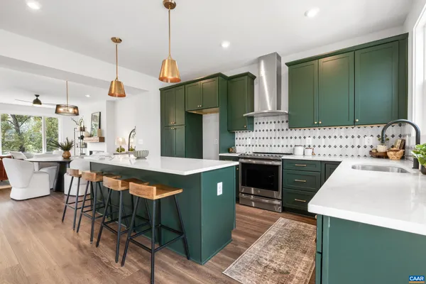 a kitchen with a stove a sink dishwasher a dining table and chairs with wooden floor