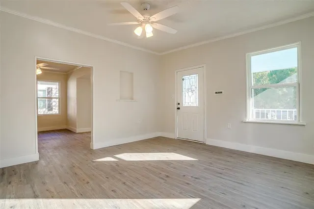 an empty room with wooden floor and windows