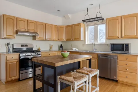 a kitchen with stainless steel appliances granite countertop a stove a sink dishwasher and a refrigerator with wooden cabinets