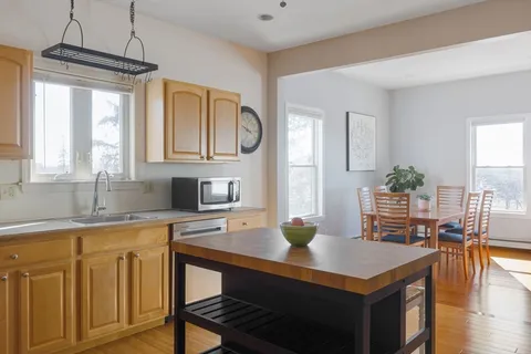 a kitchen with a sink dishwasher a dining table and chairs with wooden floor
