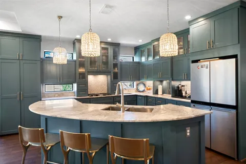 a kitchen with kitchen island granite countertop a sink cabinets and refrigerator
