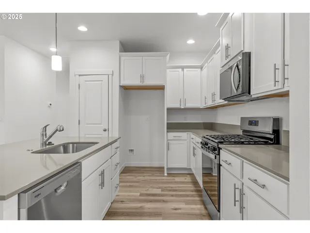 a kitchen with a sink a stove a refrigerator and white cabinets