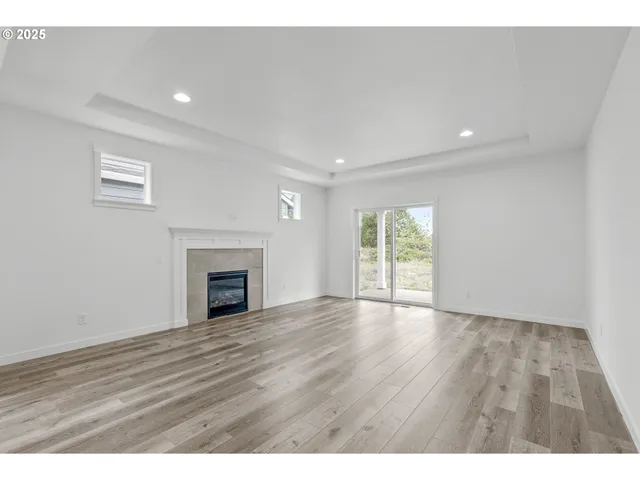 a view of an empty room with wooden floor and a kitchen