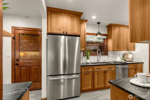 a kitchen with kitchen island granite countertop stainless steel appliances a refrigerator a sink and a counter