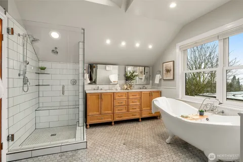a bathroom with a bathtub a mirror a shower and vanity