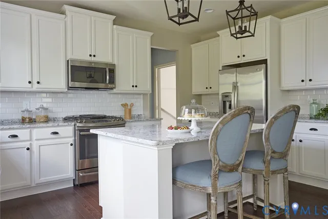 a kitchen with stainless steel appliances granite countertop a stove a sink dishwasher and white cabinets with wooden floor