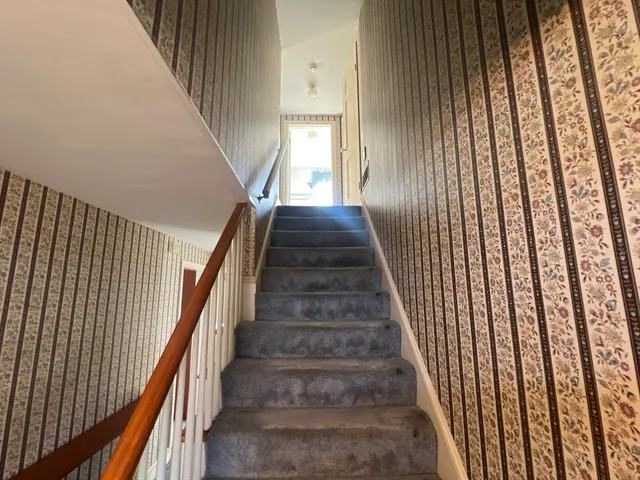 a view of a hallway with wooden floor and staircase