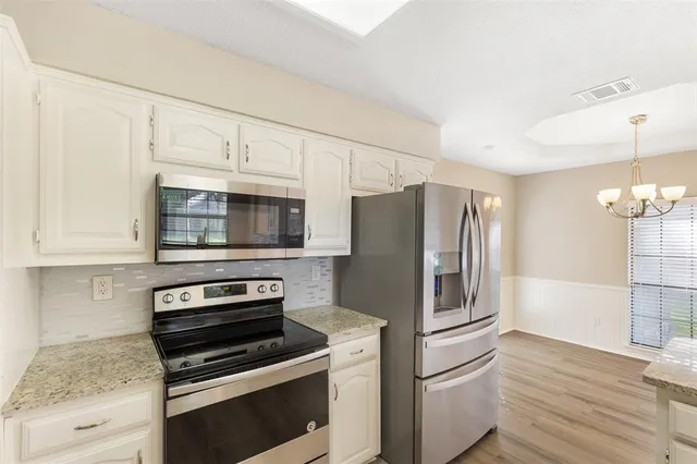 a kitchen with granite countertop a refrigerator and a stove top oven