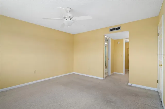 an empty room with windows and ceiling fan