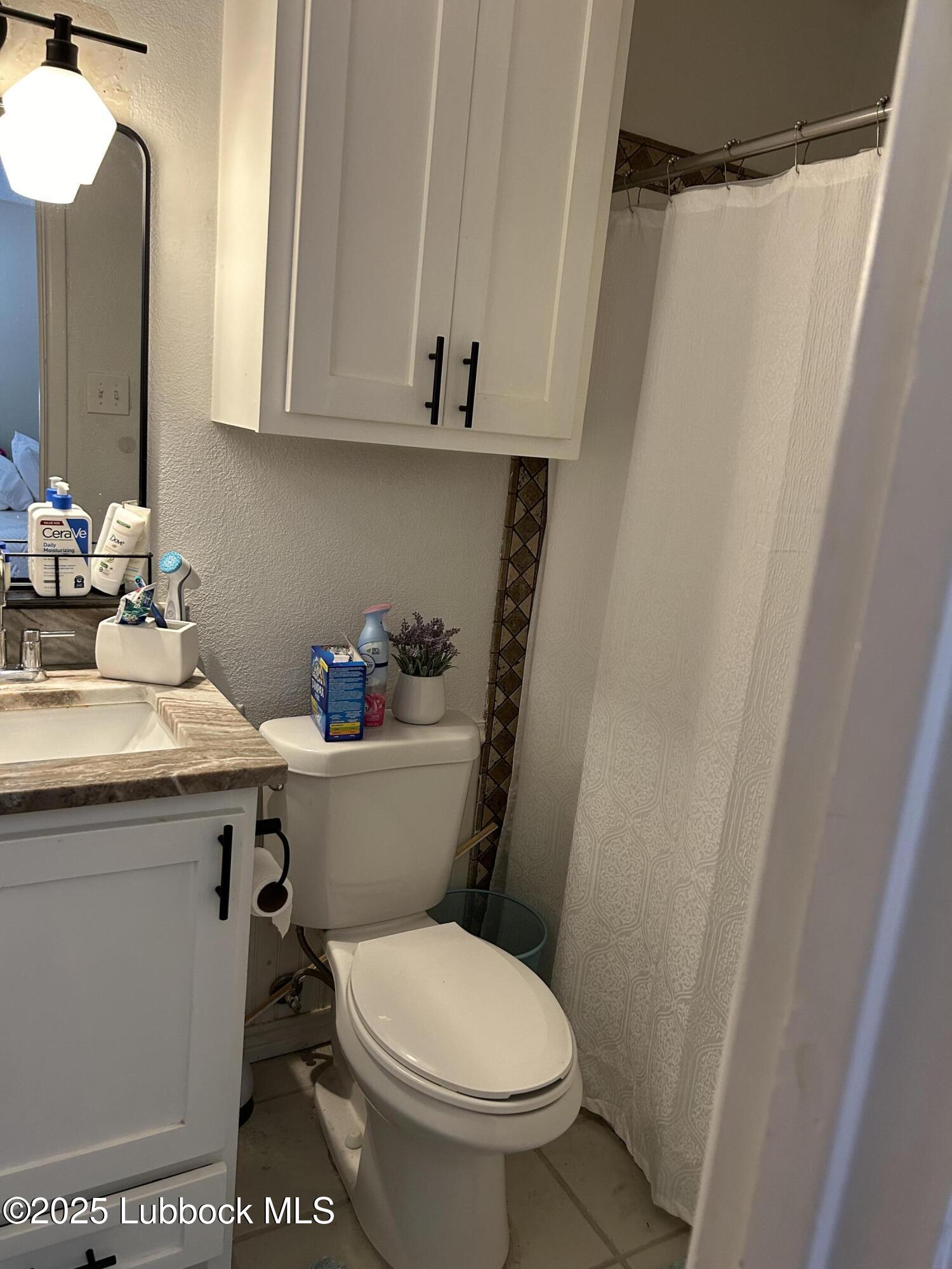 4809 8th Street Lubbock, TX 79416 - Photo 10 of 15 a bathroom with a sink a toilet and shower curtain